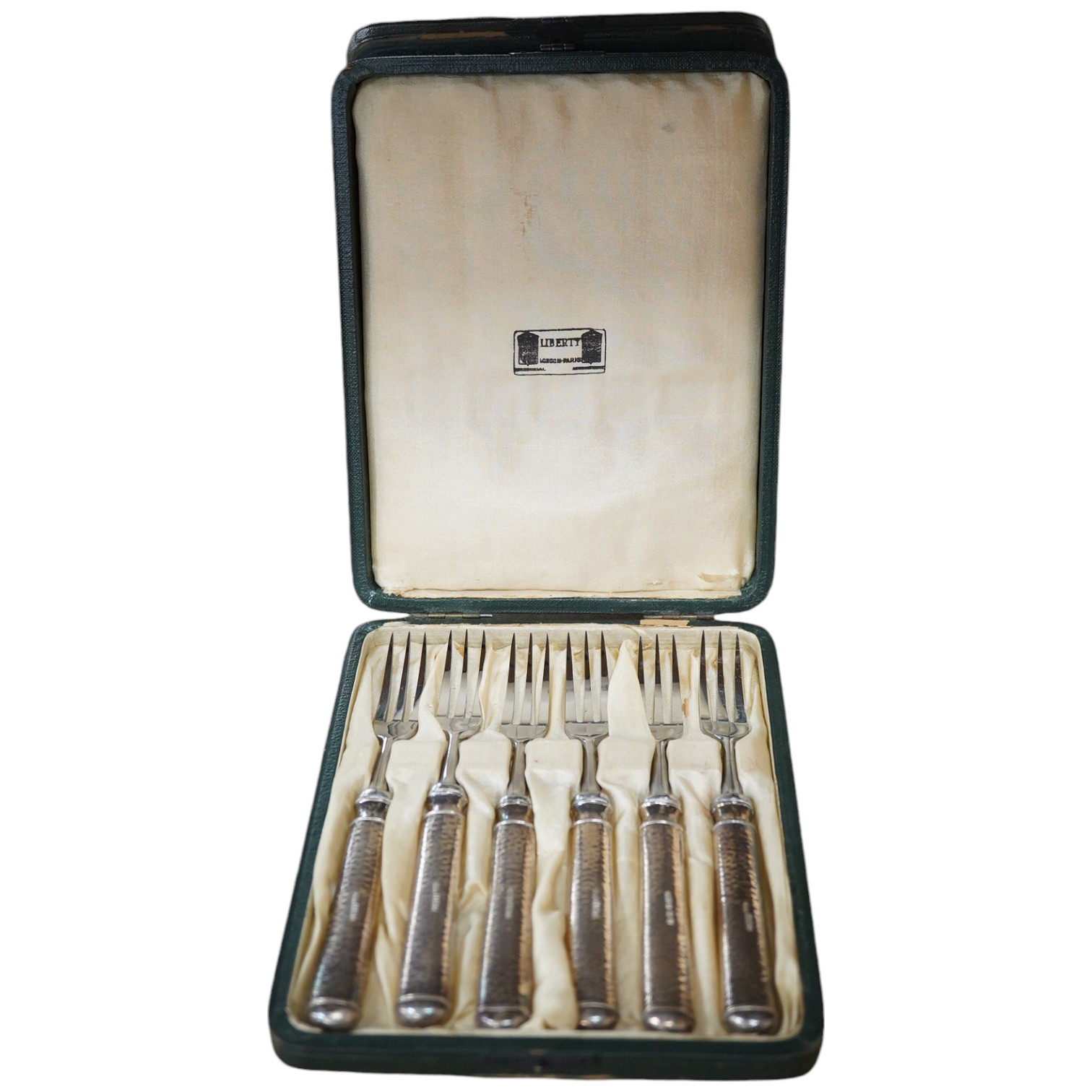 A cased set of six Edwardian silver handled pastry forks by Liberty & Co, with later? steel tines, Birmingham, 1902, 14.8cm, in Liberty & Co box. Condition - fair